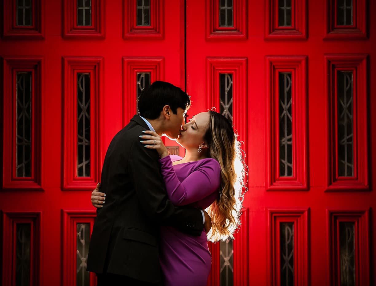 Gary and Natalie kissing in front of a red door.